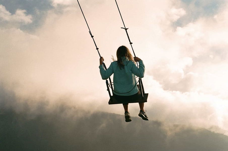 Girl on swing in the clouds